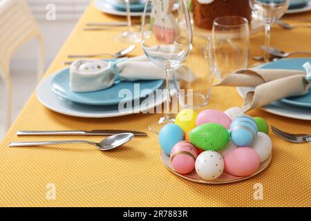 Festive table setting with painted eggs, glasses and cutlery. Easter celebration Stock Photo