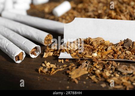 Tobacco and hand rolled cigarettes on wooden table, closeup Stock Photo