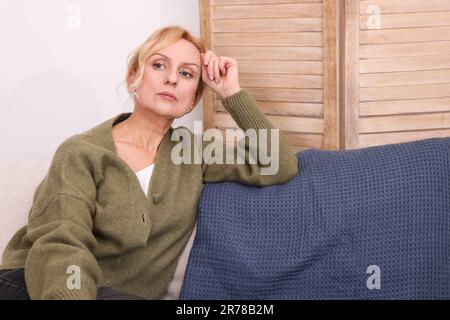 Upset middle aged woman sulking on sofa at home. Loneliness concept Stock Photo