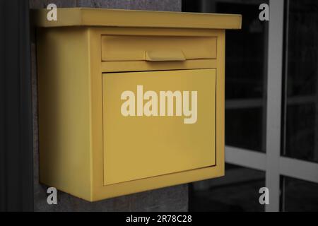 Yellow metal letter box on wall outdoors, closeup Stock Photo