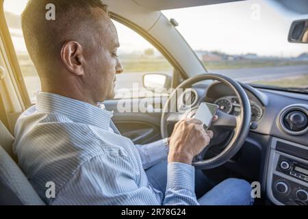 Driver using a mobile phone inside his car with copy space. Stock Photo