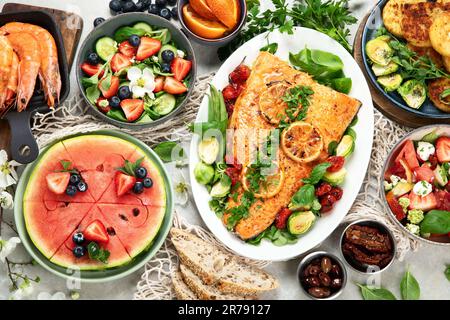 Dinner table with shrimp, fish, salads and different snacks on a white background. Top view. Stock Photo