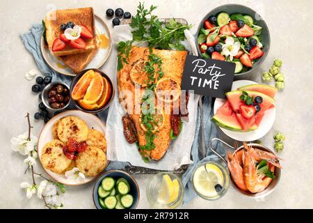 Dinner table with shrimp, fish, salads and different snacks on a white background. Top view. Stock Photo
