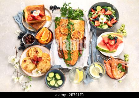 Dinner table with shrimp, fish, salads and different snacks on a white background. Top view. Stock Photo