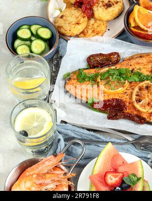 Dinner table with shrimp, fish, salads and different snacks on a white background. Top view. Stock Photo
