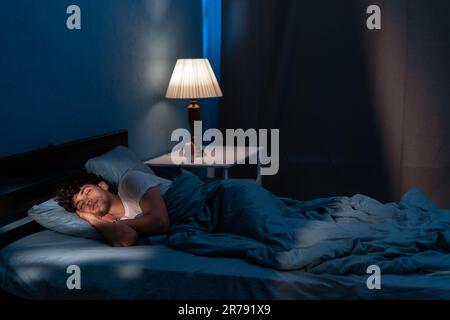 Young arabic man sleeping in bed at home at night. People, bedtime and rest concept Stock Photo