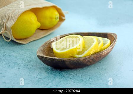 Close up image of lemon slices in a wooden bowl. Lemons in a hessian bag Stock Photo