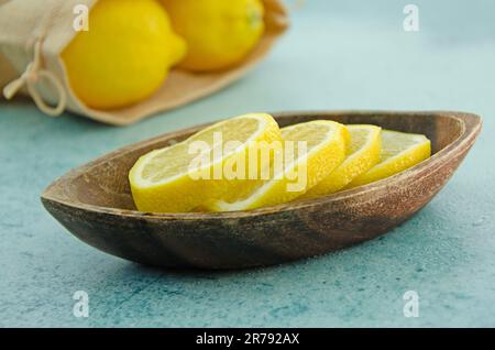Close up image of lemon slices in a wooden bowl. Lemons in a hessian bag Stock Photo