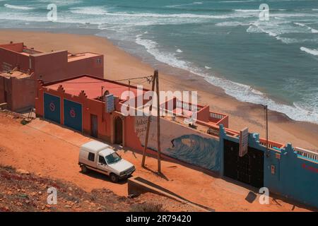 Legzira, Morocco - aerial view of Auberge Beach Club and the wild Atlantic Ocean coast on a sunny day. White van parked on ochre clay soil. Stock Photo