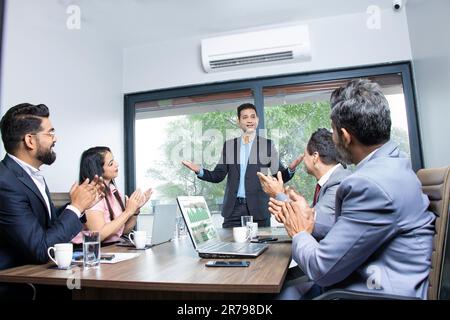 Indian businesspeople clapping and appreciating businessman at conference. Company is greeting partner for success in business work. Stock Photo