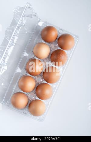 Top view of cleared plastic egg tray with 10 eggs on white background, blank space for branding design. Container for eggs in clear plastic on white b Stock Photo
