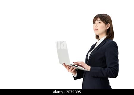 Asian business woman looking up while working on her laptop Stock Photo
