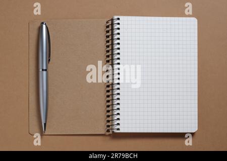 Notebook and pen on brown background close-up, top view Stock Photo