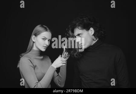 Girl scheming an evil plan of cutting off a curly hair in a man. A smart wily woman has wonderful schemes like a crook of a friend, a dark background Stock Photo