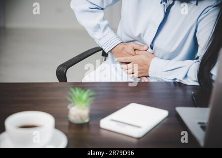 Young asian business woman person sitting at work and has stress pain in her stomach. Concept office syndrome abdomen pain from occupational disease, Stock Photo