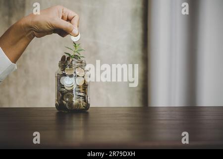 businessman holding coins putting in glass. concept saving money for finance accounting Stock Photo