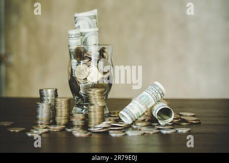 Saving money by dollars with coins in jug glass on dark background Stock Photo