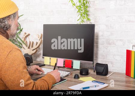 A Caucasian man sitting at a desk, working on a computer Stock Photo