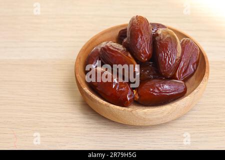 Bowl of dried dates isolated on wooden background Stock Photo
