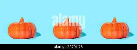 Three Ceramic pumpkins on light blue background. Decorative orange glass pumpkin. Autumn minimal concept. Halloween, thanksgiving, creative sale banne Stock Photo