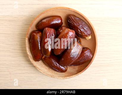 Bowl of dried dates isolated on wooden background Stock Photo