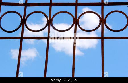 Round steel fence with blue sky and clouds background Stock Photo