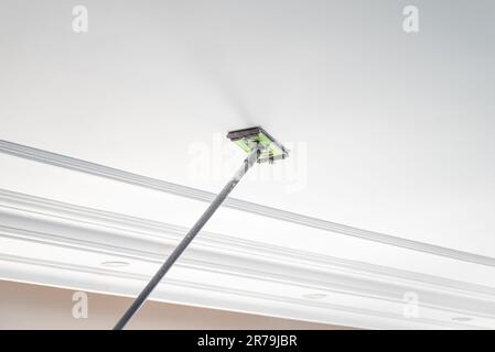 The master sanding the plaster on the ceiling of the room to be painted Stock Photo