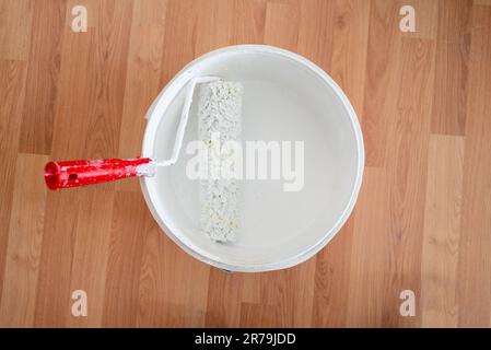 Top view of whitewash roll standing in bucket of white ceiling paint Stock Photo