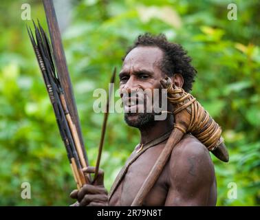 Portrait Korowai man hunter with arrow and bow. Tribe of Korowai (Kombai , Kolufo).On the June 10, 2016 in Onni Village, New Guinea, Indonesia Stock Photo