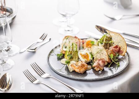 Luxury restaurant serves a modern twist on the classical ceasar salad on a dark plate. Stock Photo