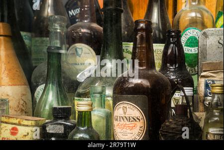 Old and dusty bottles in the outside display case of an Irish pub, collection of guinness beer bottles, shallow depth of field. Stock Photo