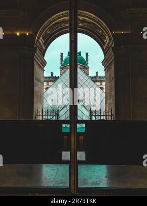The iconic entrance to the Louvre Museum in Paris, France illuminated by the bright sunlight streaming through the museum's windows Stock Photo