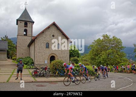 PINET, FRANCE, June 12, 2023 : Runners of the Criterium du Dauphine and the church of Pinet during last stage of this eight days cycling race. Stock Photo