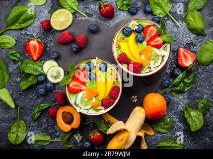 Green Smoothie in bowls for healthy breakfast. Fresh organic smoothie made from spinach, banana, spirulina,wheatgrass and lime with berries and fruits Stock Photo