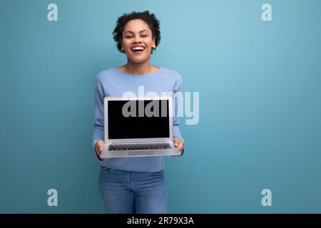 successful young afro brunette female student with a laptop demonstrates a screen with a mockup for advertising Stock Photo