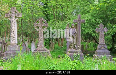 Stone crosses and grave monuments among dense greenery in Highgate Cemetery, a historic Victorian burial ground in North London, England, UK. Stock Photo