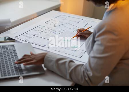 Woman architect using her laptop while working with blueprints, city plans and cadastral maps Stock Photo