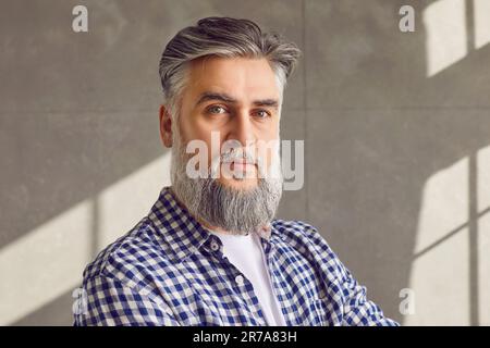Close up portrait of confident bearded mature man on grey wall background Stock Photo