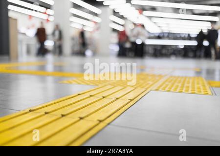 Yellow tactile tiles for the blind laid on a tiled floor in a store interior Stock Photo