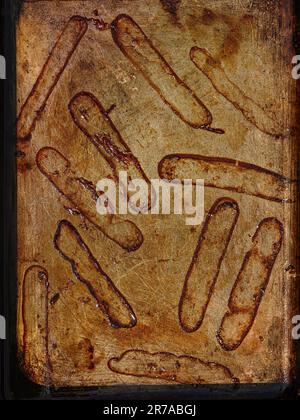 the outlines left by sausages after they have been cooked in an oven tray Stock Photo