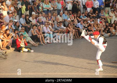 A young adult male performing artist wearing a white suit and dress shoes, kicking one leg up in the air in a dynamic motion Stock Photo