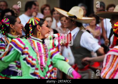 Three dancers in colorful, ornate costumes captivate a lively audience, as they perform an entertaining dance routine Stock Photo