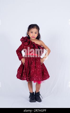 A young woman in a red dress stands with her hands resting on the back of her head, looking content and confident Stock Photo