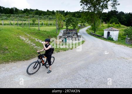 Woman tourist drinking, cyclists on a cycling trip around Istria Peninsula in Slovenia, cycling, passing vineyards, small chapel, abitanti, slovenia Stock Photo