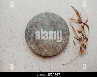 Marble gray round podium and dry eucalyptus branch on beige texture background. Place, background for cosmetics. Top view. Copy space Stock Photo