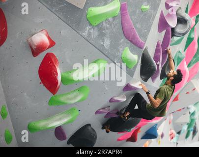 Dramatic action shot looking down on man climbing wall at indoor activity centre Stock Photo