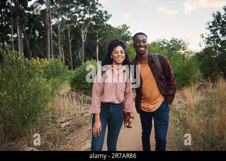 Smiling young multiethnic couple standing on a trail during a hike Stock Photo