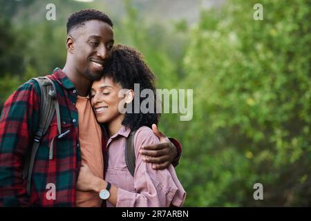 Smiling young multiethnic couple hugging during a break from a hike Stock Photo