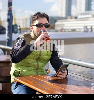 Man drinking a beer while sitting in a bar at the harbor Stock Photo