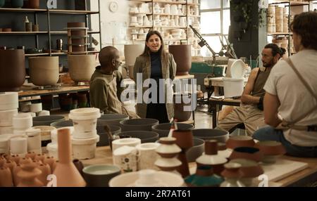 Smiling manager talking with workers in a ceramics studio Stock Photo